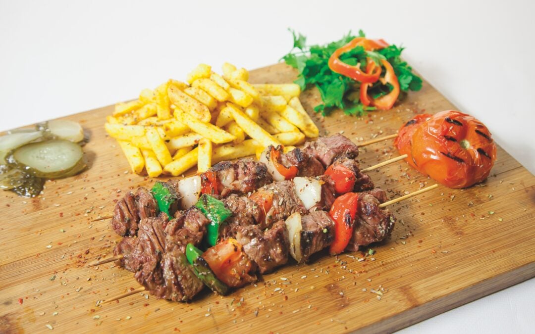 切菜板上放着烤肉串、蔬菜串、薯条和烤番茄