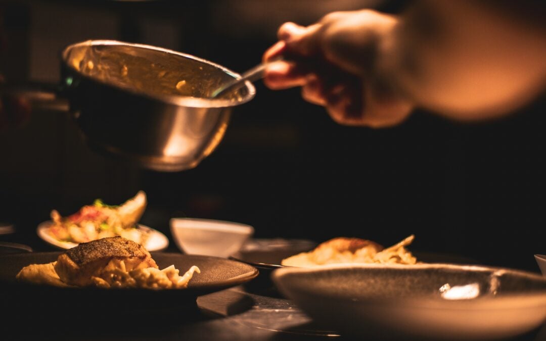 厨师正准备在肉盘上淋酱汁